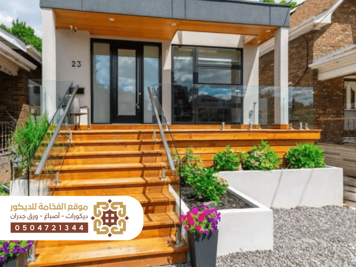 مدخل أنيق لمنزل حديث يتميز بدرج خارجي واسع يؤدي إلى الباب الرئيسي، مع تفاصيل معمارية عصرية ولمسات من الحجر الطبيعي.