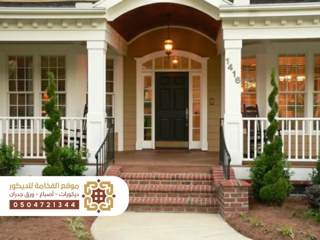 مدخل أنيق لمنزل عصري يتضمن درجًا خارجيًا واسعًا يؤدي إلى الباب الرئيسي، محاط بتفاصيل معمارية جذابة.