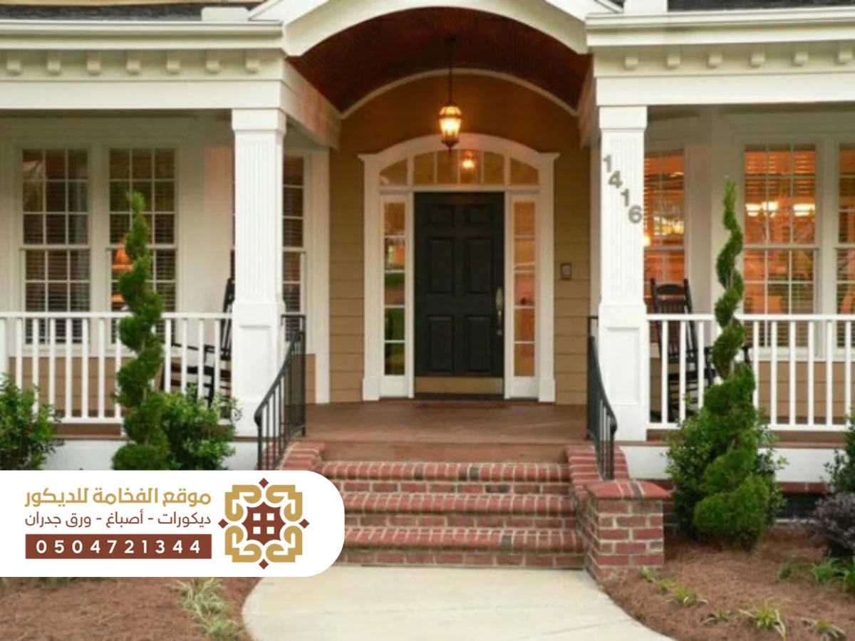 مدخل أنيق لمنزل عصري يتضمن درجًا خارجيًا واسعًا يؤدي إلى الباب الرئيسي، محاط بتفاصيل معمارية جذابة.